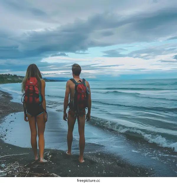 Couple Walking on the Beach at Sunset with Backpacks