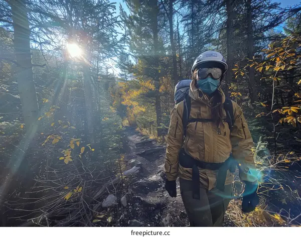 A woman in protective gear walks through a forest
