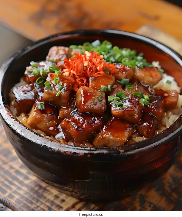 A bowl of diced pork with rice topped with spring onions and chillies