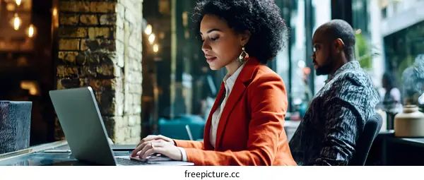 Woman in Orange Blazer Working on Laptop in Cafe