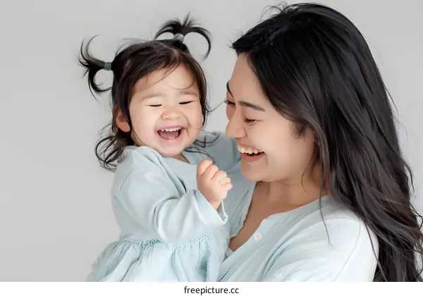 Smiling Asian Mother Holding her Daughter