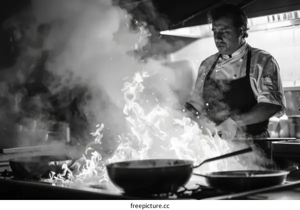 Black and white photo of a chef cooking with flames in the kitchen