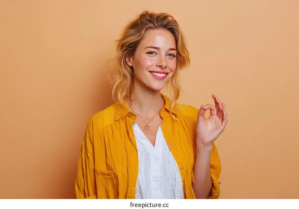 Smiling Woman in Mustard Yellow Shirt Making Ok Gesture