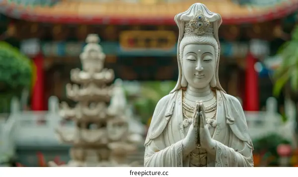 White marble statue of a bodhisattva with hands clasped in prayer