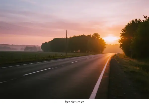 Sunrise over a quiet country road with trees on both sides