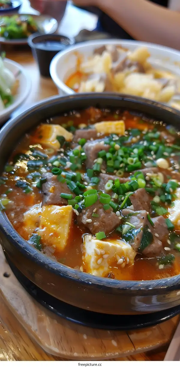 A bowl of Korean spicy tofu soup with beef and scallions