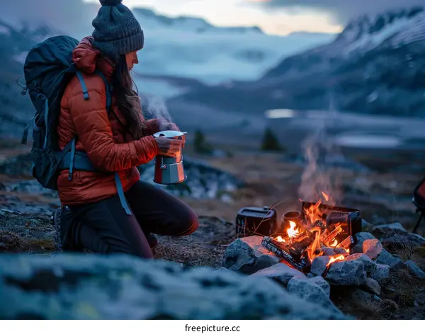 woman making coffee on a camping stove in the mountains
