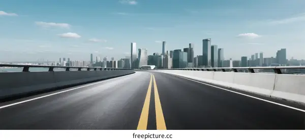 Smooth Road Leading to Modern City Skyline with Clear Blue Sky