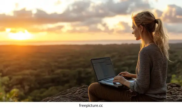 Woman Working on Laptop Outdoors at Sunset