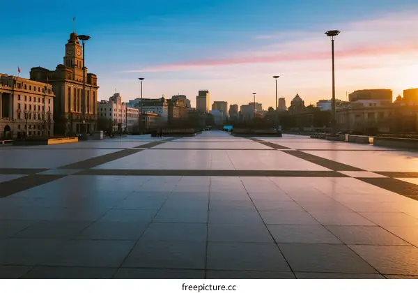 Sunset view of an open square with urban buildings in the background