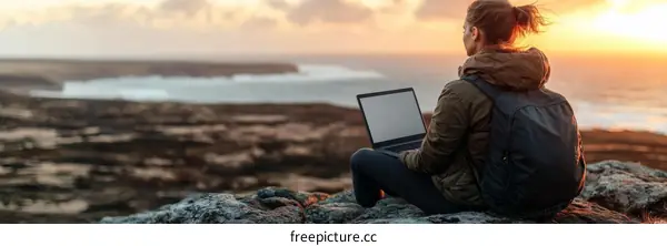 Woman Working on a Laptop at Sunset Over the Ocean
