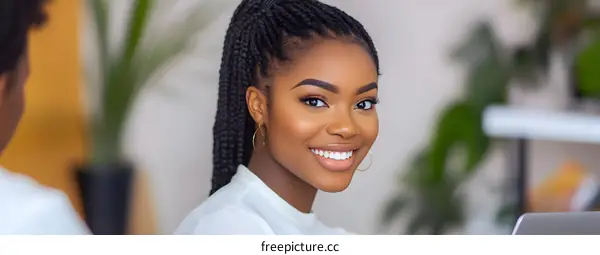 Smiling Black Woman in a White Shirt With Braided Hair