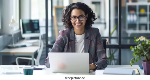 Smiling businesswoman working on laptop in modern office