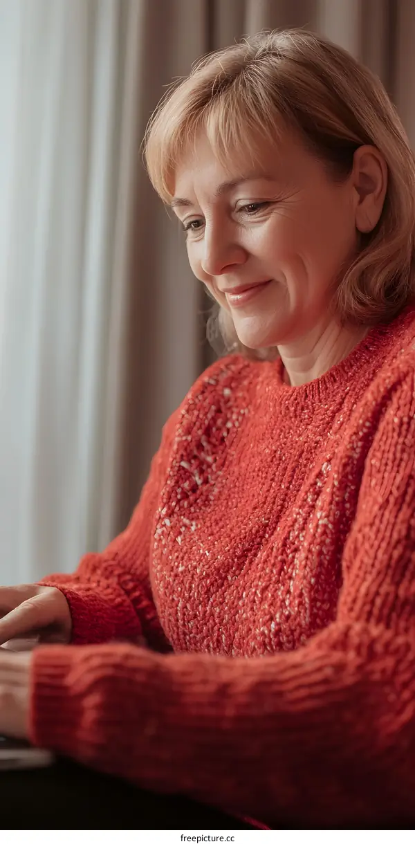 Smiling Woman Working On Laptop Wearing Red Sweater