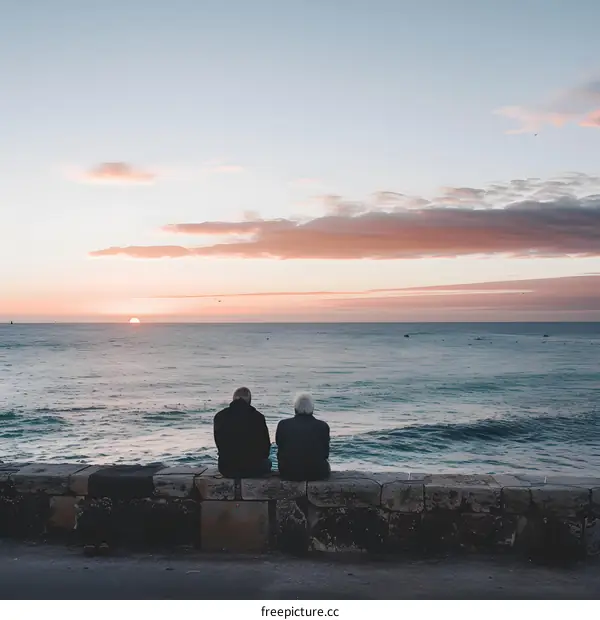Two Men Sitting on a Wall Watching the Sunset over the Ocean