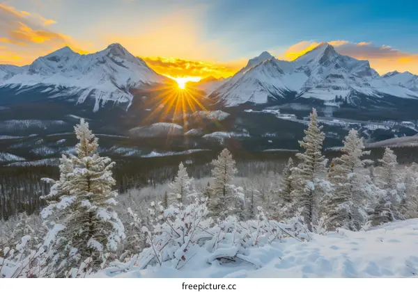 The sun sets behind snow-capped mountains in Banff National Park, Canada