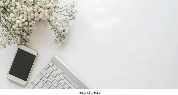 Minimalist White Background With Flowers Keyboard and Phone