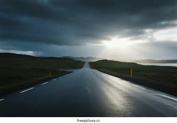 Long road under dark clouds with sunlight breaking through