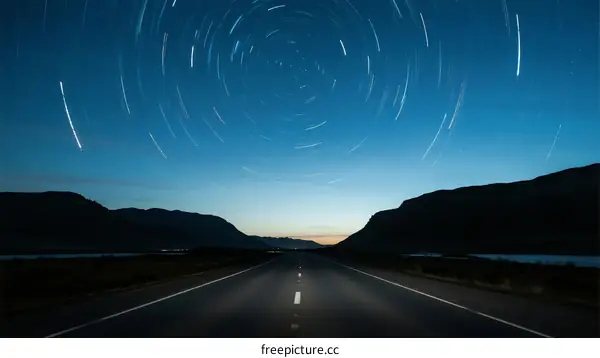 Night Road with Star Trails Over Mountain Landscape