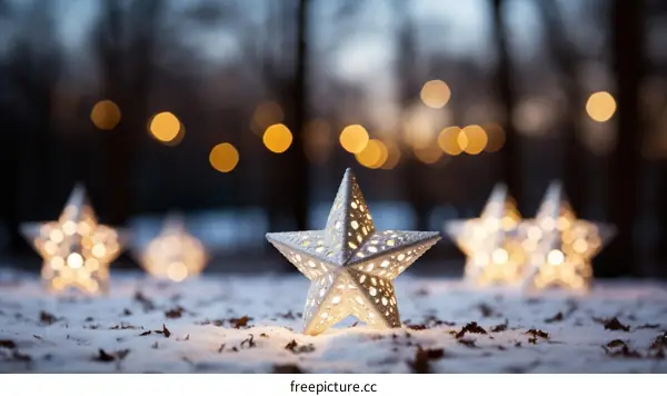 Five silver metal stars on snow with blurred lights in background