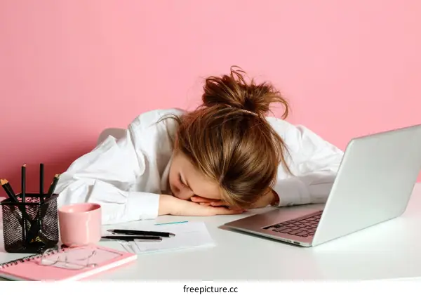 Tired Woman Sleeping on Desk with Laptop