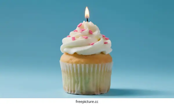 Delicious vanilla cupcake with lit candle on blue background