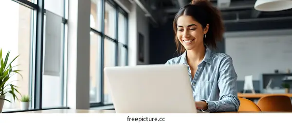 Smiling Woman Working on Laptop in Modern Office
