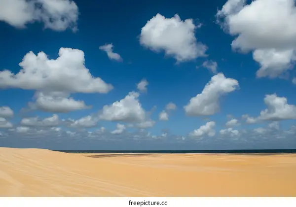 Blue Sky with White Clouds over Sand Dunes and Ocean