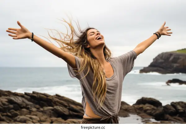 carefree woman standing on a rocky beach with arms outstretched