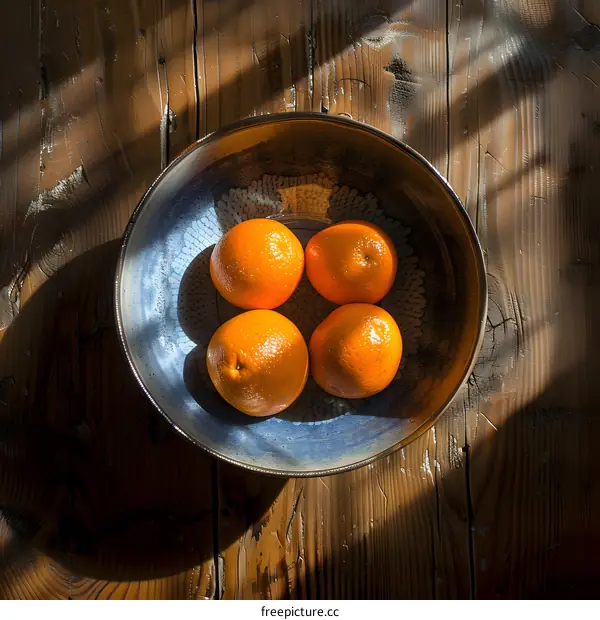 Four Oranges in a Blue Bowl on a Wooden Table