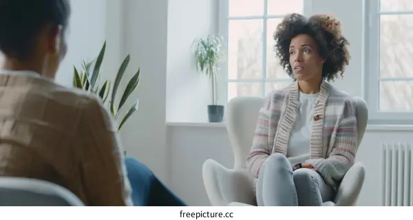 A woman is talking to another person while sitting in a chair