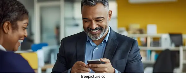 Smiling Man and Woman Looking at Phone in Office