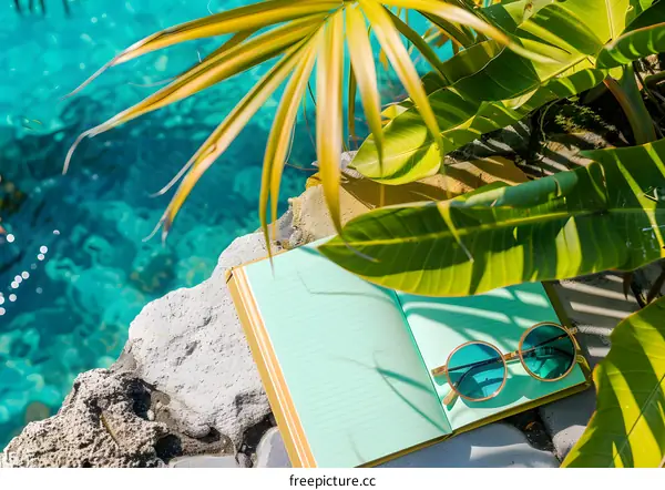 Summer Vacation Essentials: Notebook, Sunglasses, and Palm Leaves