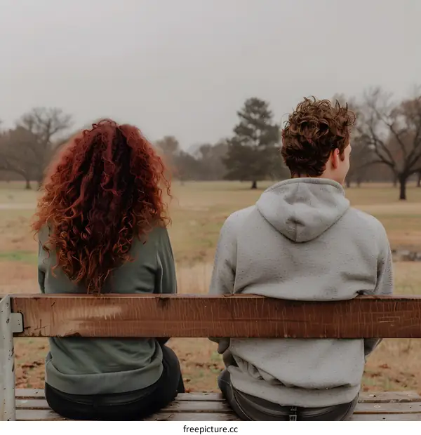 Couple Sitting on Bench Back to Back in Park