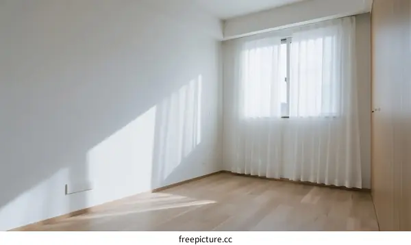Empty room with white walls and wooden floor near window