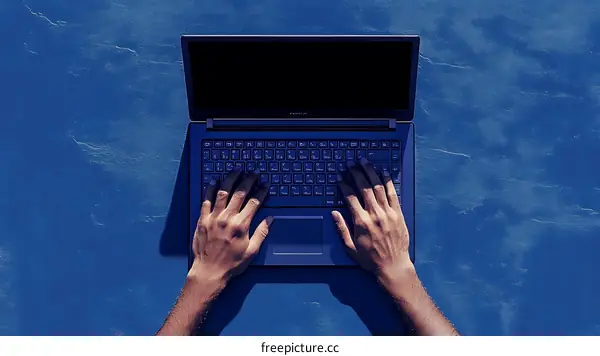 Person Working on a Laptop on a Blue Surface