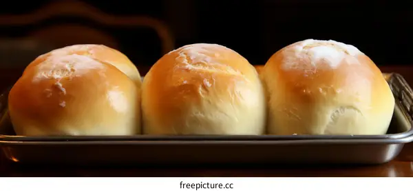 Four white bread rolls on a metal baking sheet