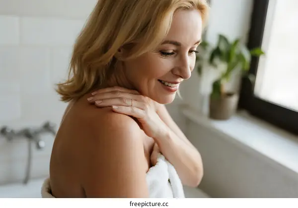 Mature Woman Applying Lotion on Shoulders in Bathroom