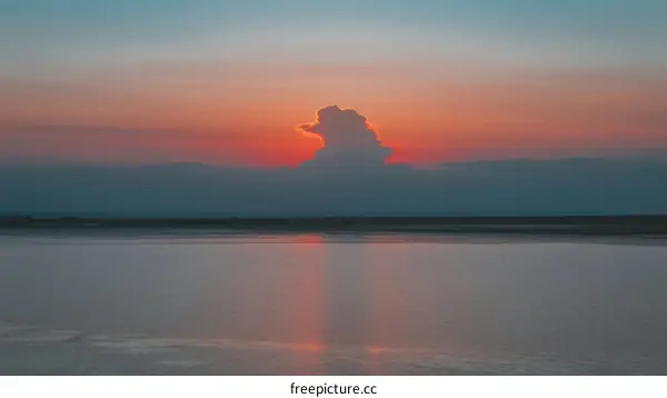 A Beautiful Sunset Over a Calm Body of Water with a Cloud in the Sky