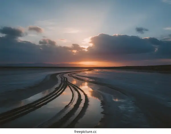 Beautiful Sunset over a Tranquil Beach with Tire Tracks