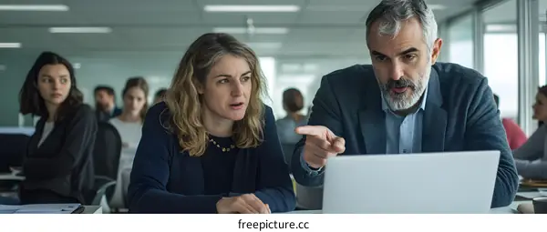 Business Professionals Meeting In Office Looking At Laptop