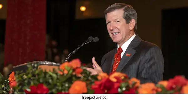 Man in Suit Speaking at a Podium with Flowers