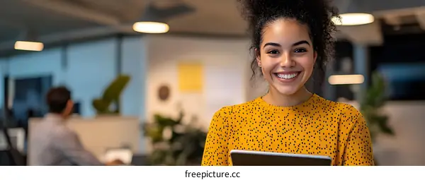 Smiling Woman Holding a Tablet in a Modern Office