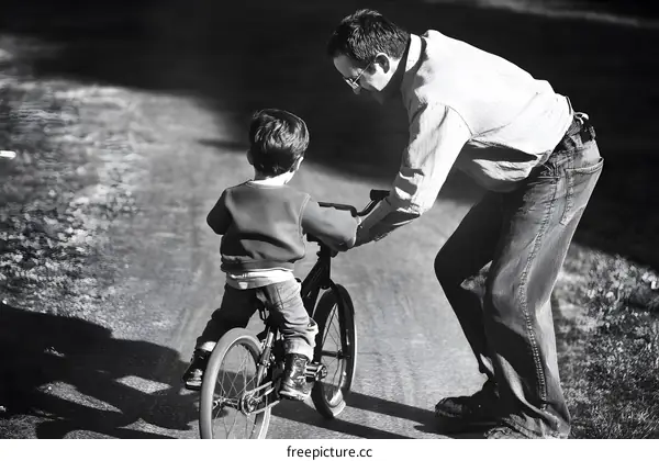 Father Helping Son Learn To Ride Bike
