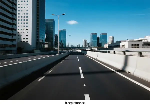 Empty urban highway with modern skyscrapers under clear blue sky