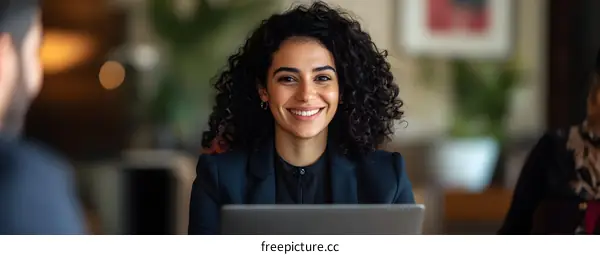 Smiling Businesswoman Working on Laptop During Meeting