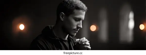 A young man with short hair wearing black hoodie looking down