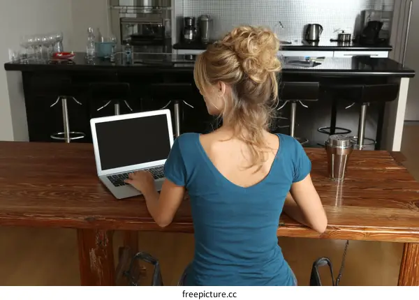 Woman Working on Laptop in Modern Kitchen