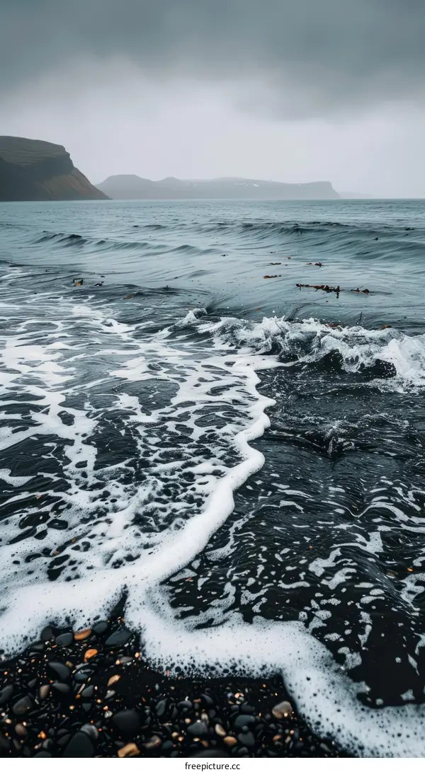 Dramatic Black Sand Beach with Stormy Sea and Mountain Landscape in Iceland