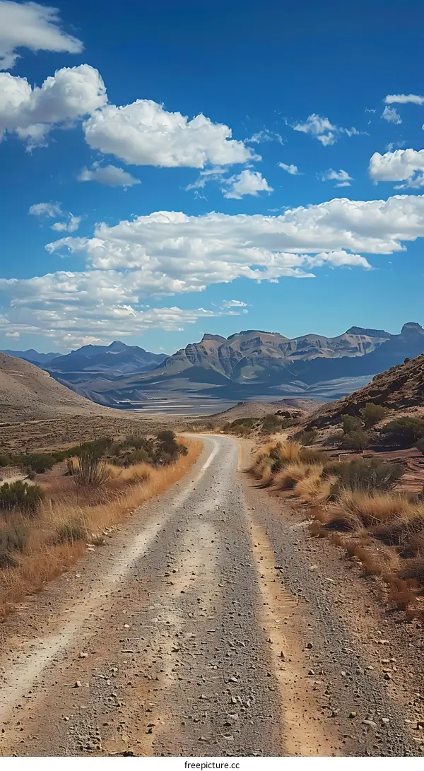 Gravel Road to the Mountains Under a Cloudy Sky